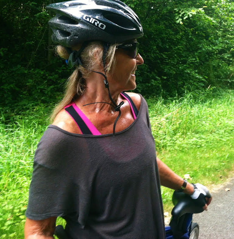 Anastasia on her bike with a helmet on, looking back over her shoulder.