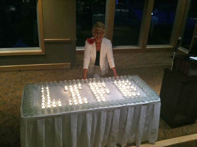 Anastasia leaning close to a table with candles arranged into the word LIFE.