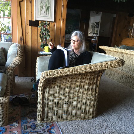 Cindy Bohnett writing on a wicker sofa inside.