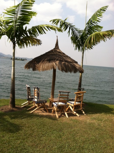 Waterside table with palms and thatch umbrella.