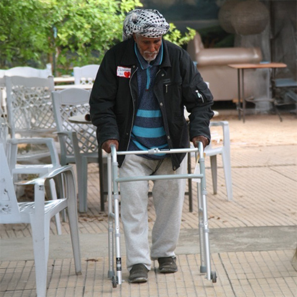 A gentleman walking in a courtyard with his walker.