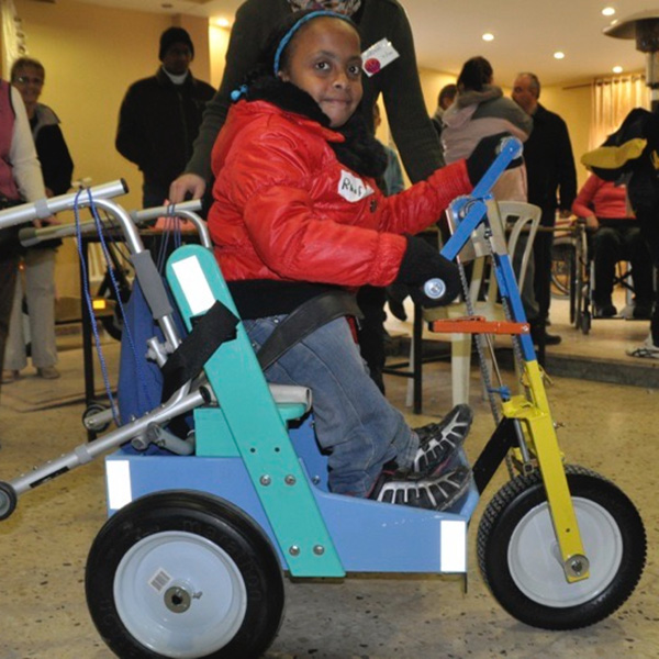 Young girls on a mobility scooter, smiling.