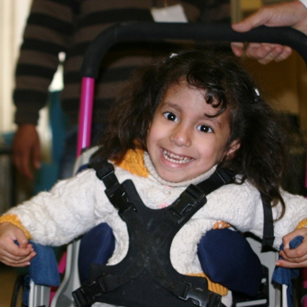 Young girl with vibrant smile sitting in a wheelchair.