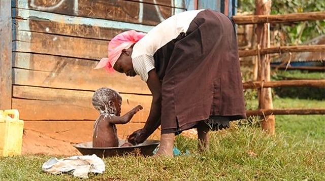 Mother bathing her child outside in Kenya.
