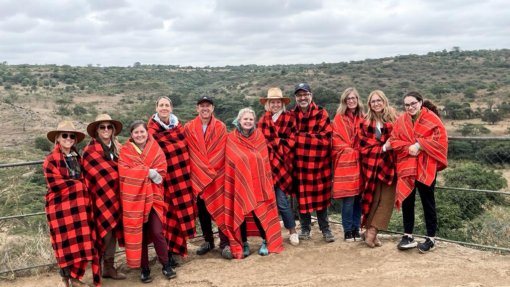 Group shot of fellow travelers for TIRZAH in Kenya, all wrapped in Maasai blankets in reds.